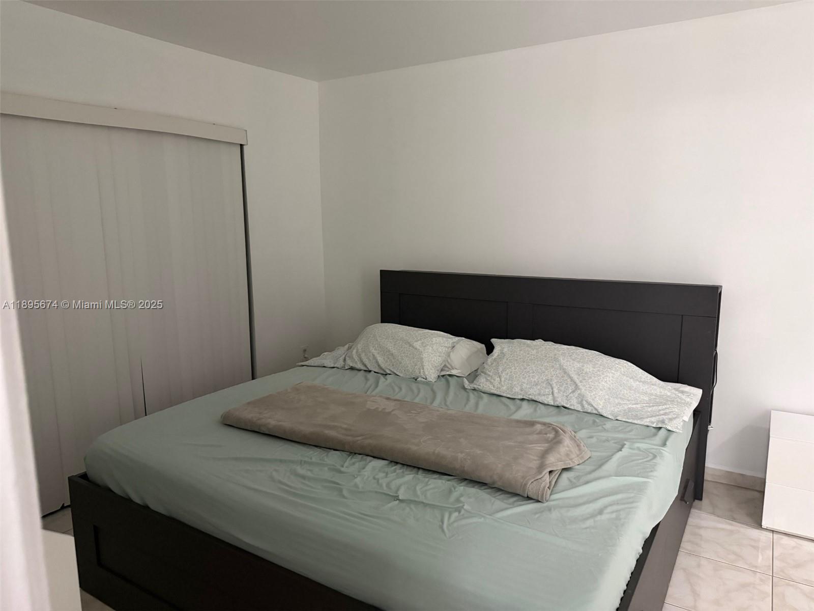 15620 Southwest 80th Street, Unit H205 Miami, FL 33193 - Photo 6 of 12 a bedroom with a bed and a night stand