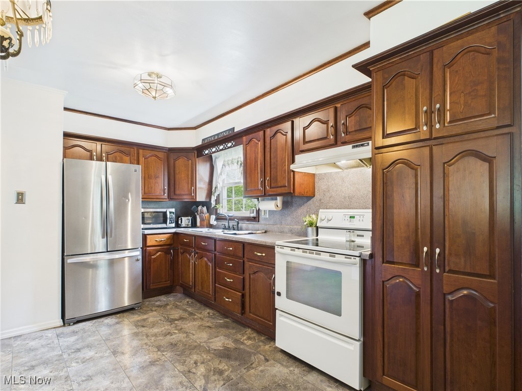 326 Highway 7 Powhatan Point, OH 43942 - Photo 6 of 32 Kitchen featuring stainless steel appliances, under cabinet range hood, ornamental molding, a sink, and light countertops