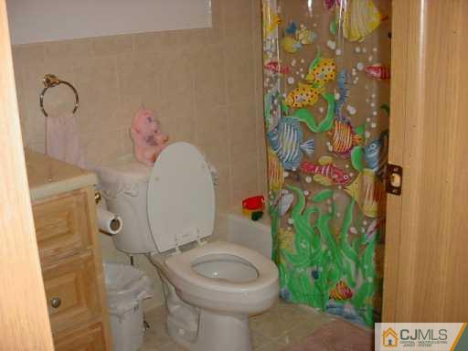 6606 Hana Road Edison, NJ 08817 - Photo 5 of 8 a white toilet sitting next to a shower curtain