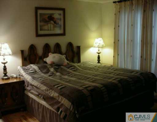 6606 Hana Road Edison, NJ 08817 - Photo 6 of 8 a bed room with a bed and a lamp