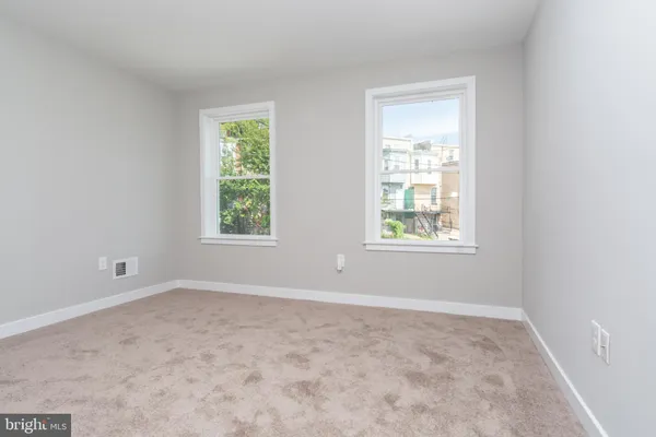 a view of an empty room with wooden floor and a fireplace