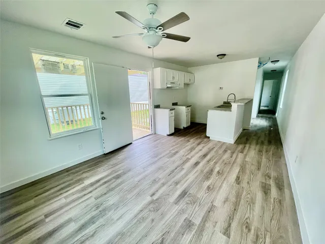 a view of a room with wooden floor and a ceiling fan