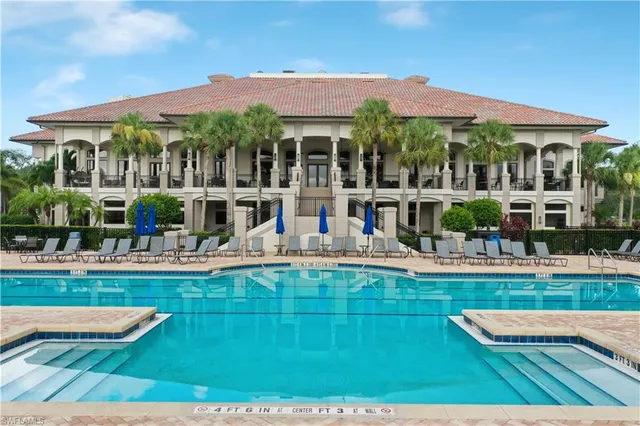 a view of a house with swimming pool lawn chairs and a dining table