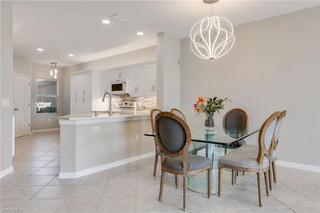 a kitchen with kitchen island granite countertop a dining table chairs and a refrigerator