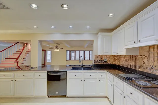 a kitchen with stainless steel appliances granite countertop a stove a sink and a white cabinets