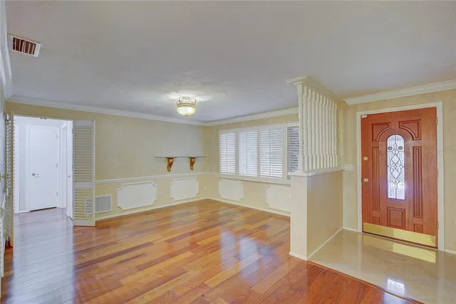 a view of empty room with wooden floor and fan