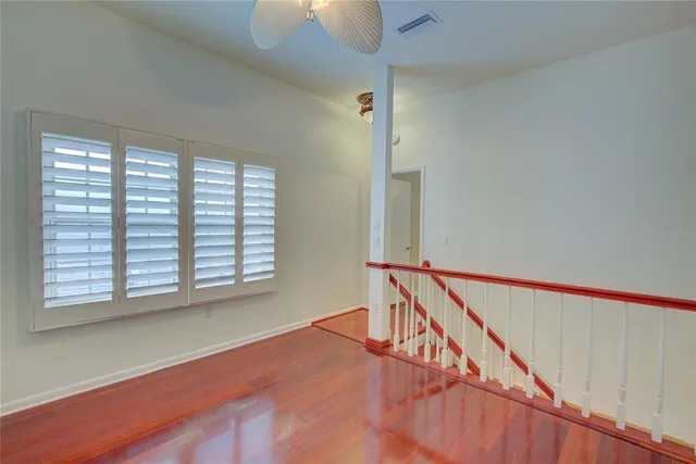 a view of an empty room with wooden floor and stairs
