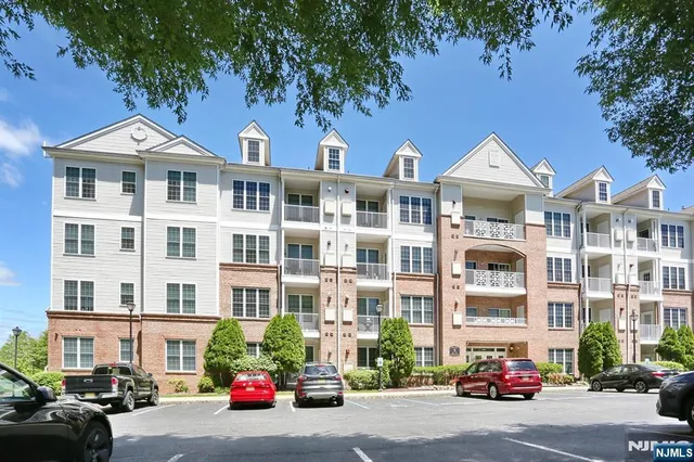 a front view of a building with lot of cars and trees