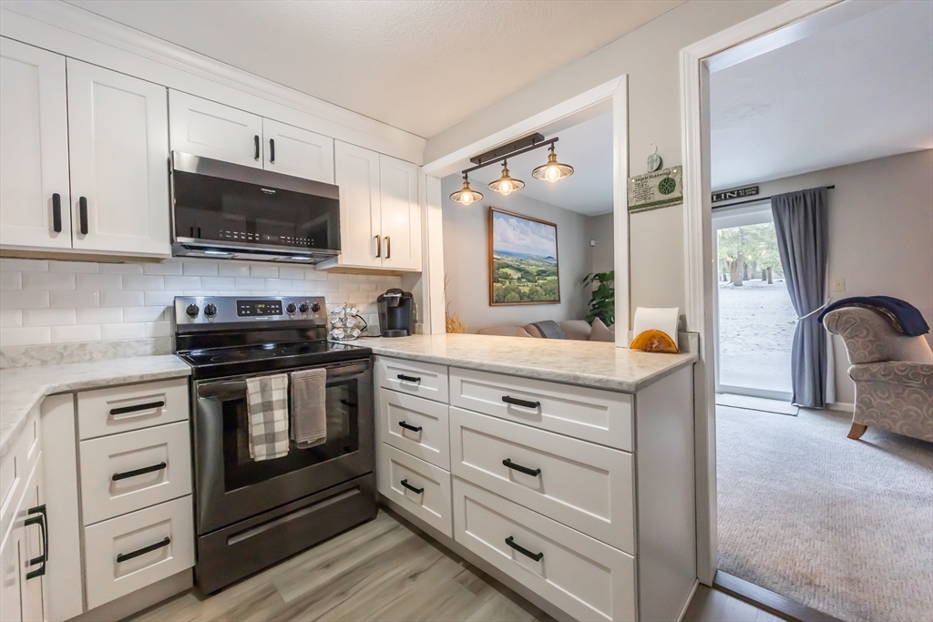 99 Stone Ridge Road, Unit 99 Franklin, MA 02038 - Photo 11 of 39 a kitchen with stainless steel appliances white cabinets and a stove top oven