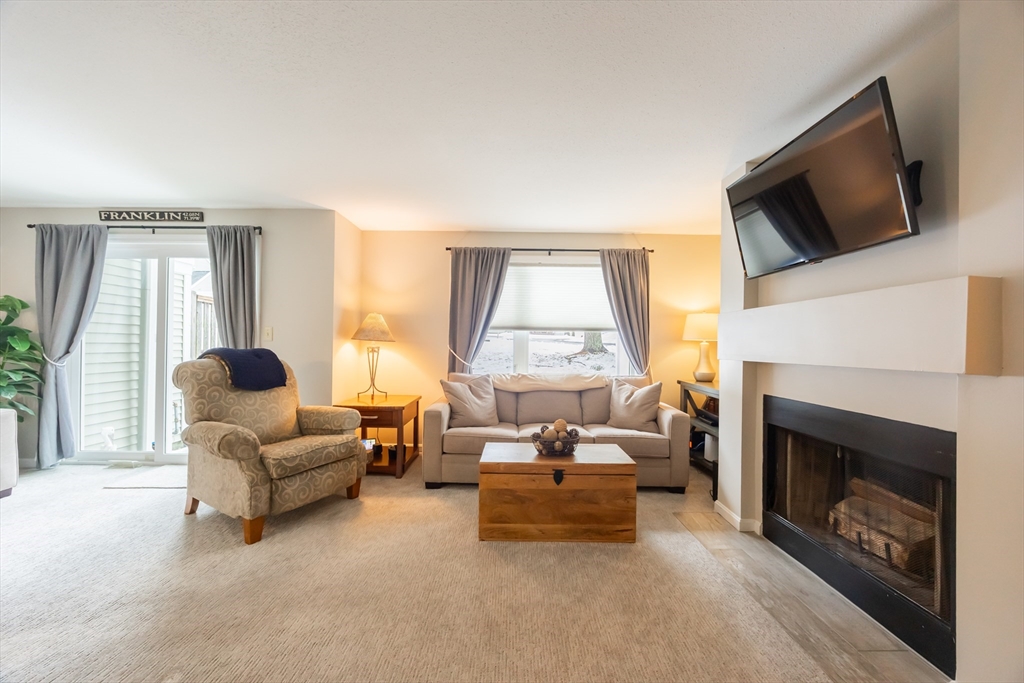 99 Stone Ridge Road, Unit 99 Franklin, MA 02038 - Photo 17 of 39 a living room with furniture a fireplace and a flat screen tv