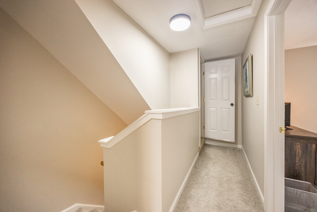99 Stone Ridge Road, Unit 99 Franklin, MA 02038 - Photo 27 of 39 a view of a hallway with white walls and stairs