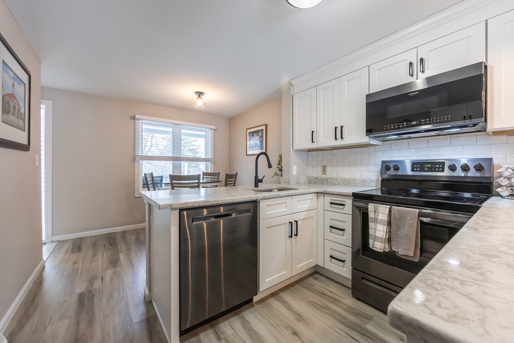 99 Stone Ridge Road, Unit 99 Franklin, MA 02038 - Photo 7 of 39 a kitchen with stainless steel appliances a stove microwave and sink