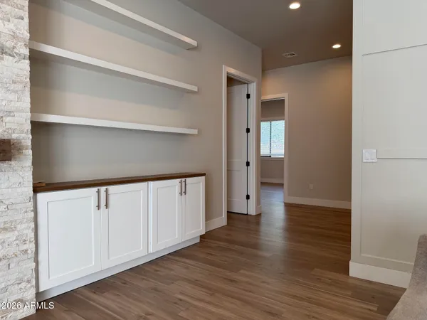 a view of a hallway with wooden floor and a bathroom