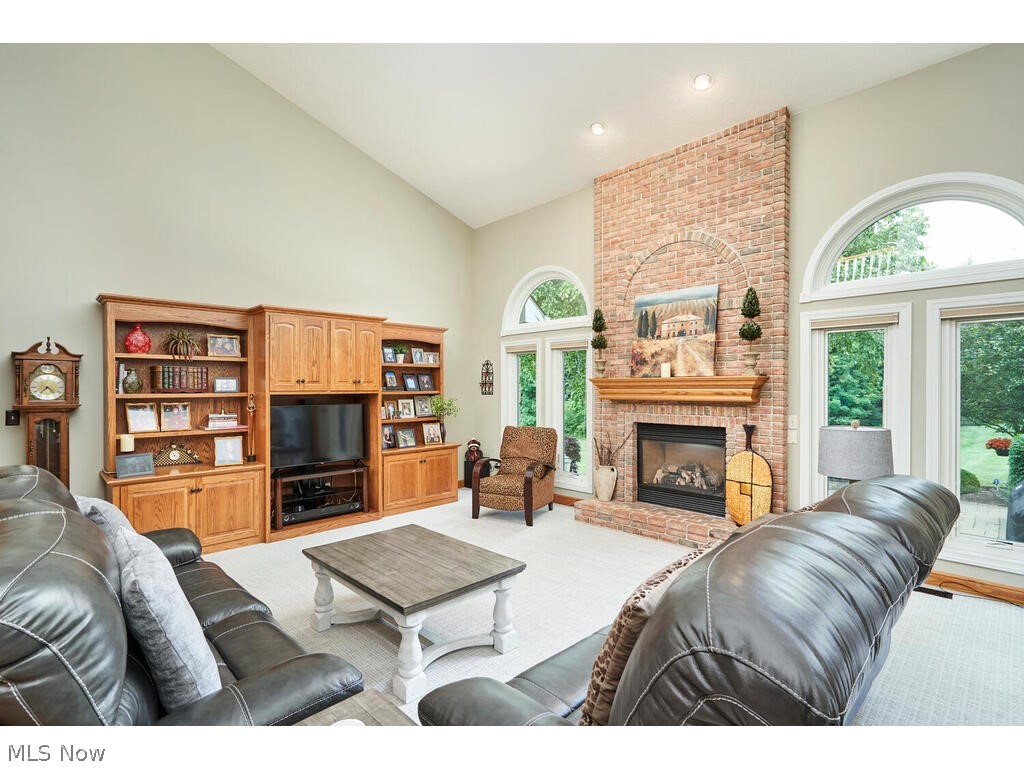 3735 Roberts Ridge Akron, OH 44333 - Photo 6 of 45 Living room featuring a fireplace, brick wall, a healthy amount of sunlight, high vaulted ceiling, and light colored carpet