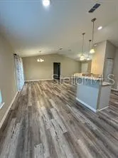a view of a kitchen with kitchen island a sink wooden floor and a refrigerator