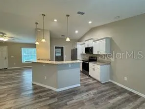 a large kitchen with kitchen island a white counter space and a refrigerator