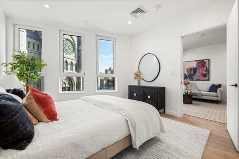a bedroom with a bed a potted plant and dresser