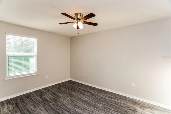 an empty room with wooden floor fan and windows