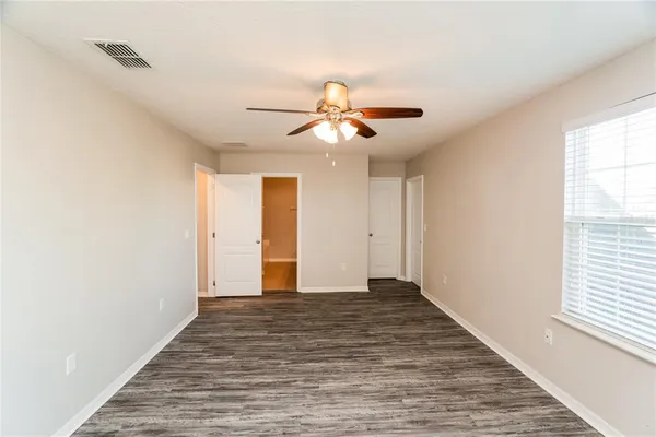 a view of an empty room with window and chandelier fan