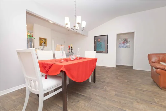 a kitchen with stainless steel appliances granite countertop a stove top oven a sink dishwasher a dining table and chairs with wooden floor