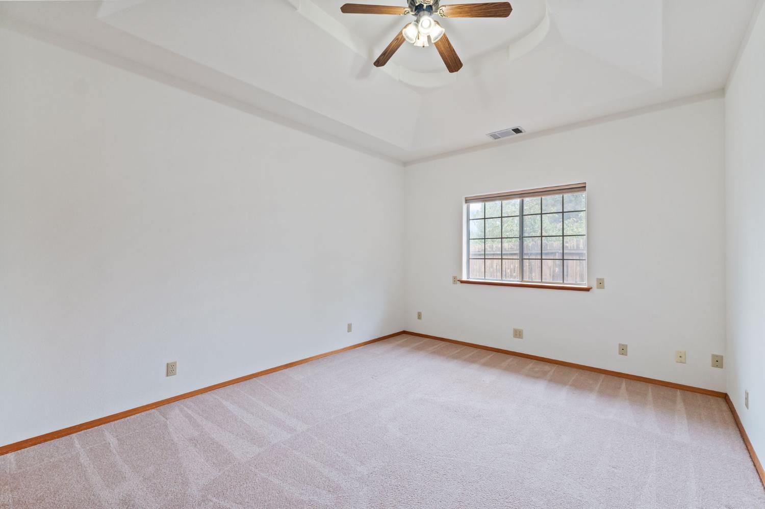 7357 East Dennett Avenue Fresno, CA 93737 - Photo 45 of 84 an empty room with a chandelier fan and windows
