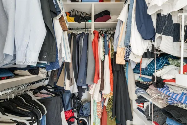 a view of walk in closet with clothes and shoes