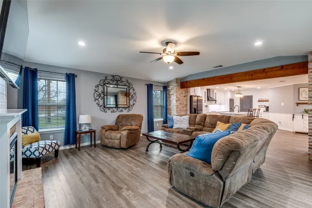 a living room with furniture two large window and a wooden floor