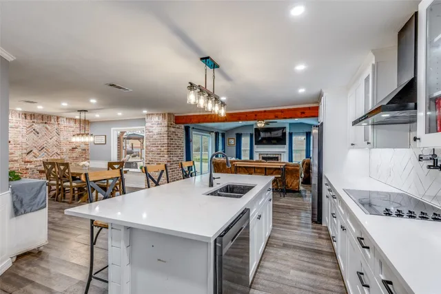 a kitchen with stainless steel appliances granite countertop a dining table chairs refrigerator and microwave