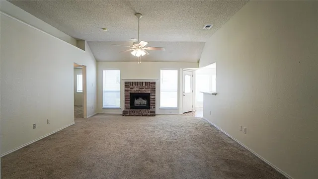 an empty room with fireplace ceiling fan and windows