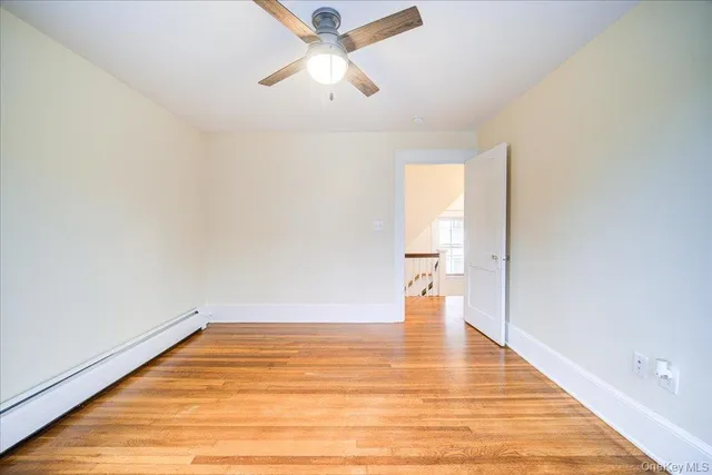 an empty room with wooden floor chandelier fan and windows