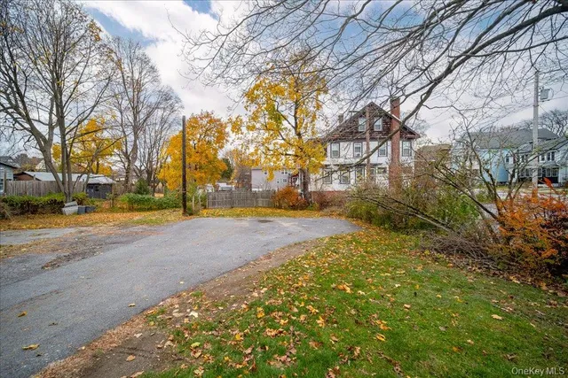 a view of a large white house with a big yard and large trees