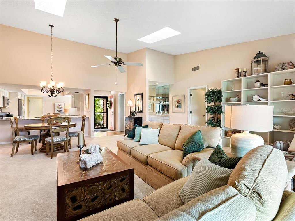 6094 Wilshire Boulevard, Unit 8 Sarasota, FL 34233 - Photo 13 of 42 a living room with furniture a chandelier and a dining table