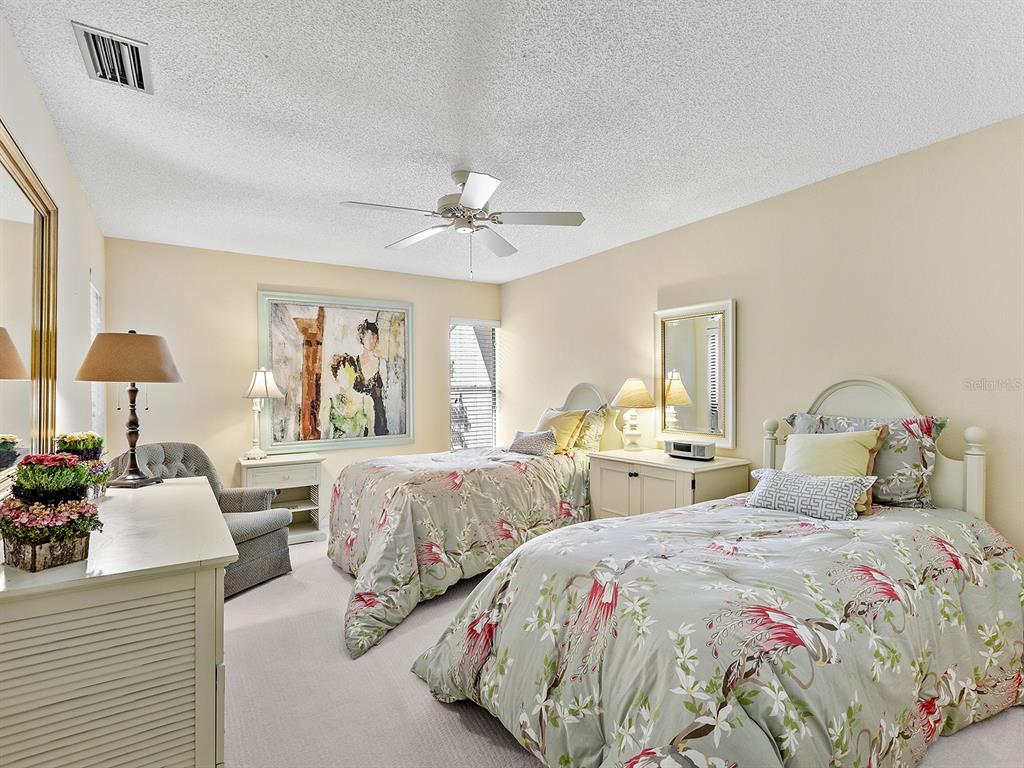 6094 Wilshire Boulevard, Unit 8 Sarasota, FL 34233 - Photo 15 of 42 a bedroom with two beds and a chandelier