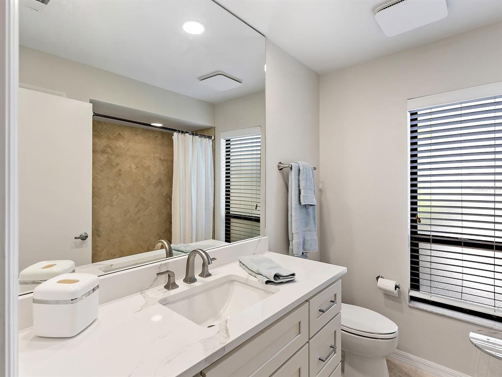 6094 Wilshire Boulevard, Unit 8 Sarasota, FL 34233 - Photo 17 of 42 a bathroom with a sink a toilet and a large mirror