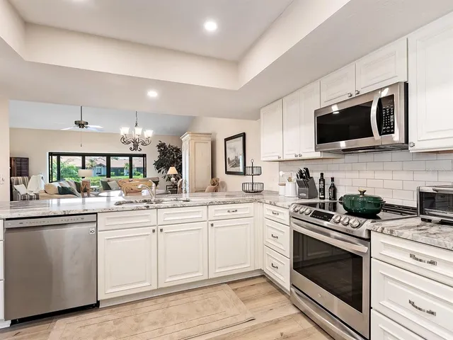 a kitchen with stainless steel appliances granite countertop a stove top oven a refrigerator and a sink