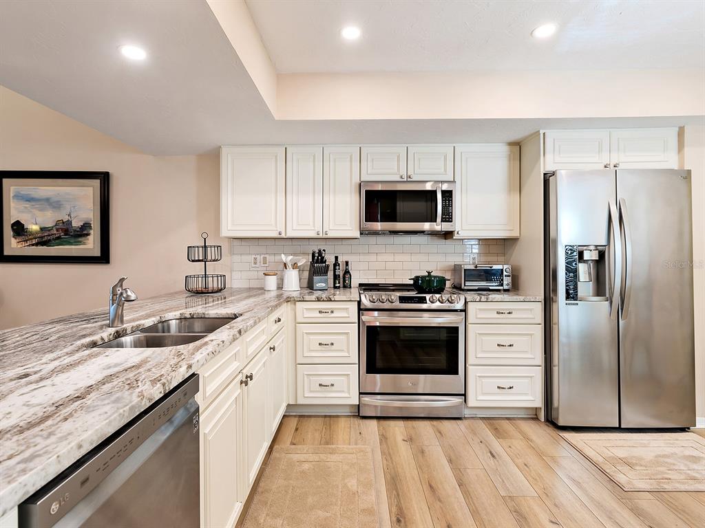 6094 Wilshire Boulevard, Unit 8 Sarasota, FL 34233 - Photo 6 of 42 a kitchen with stainless steel appliances granite countertop a stove top oven a refrigerator and a sink