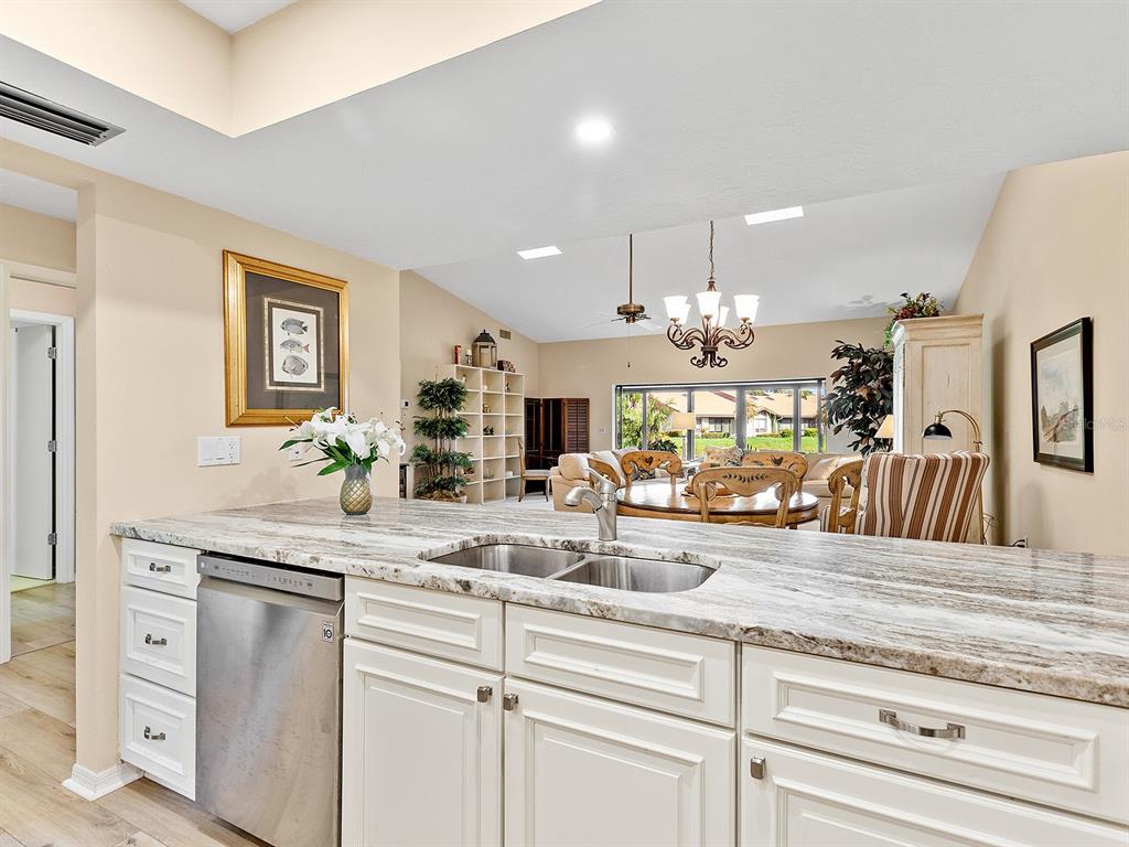 6094 Wilshire Boulevard, Unit 8 Sarasota, FL 34233 - Photo 8 of 42 a view of living room with granite countertop white cabinets and chandelier