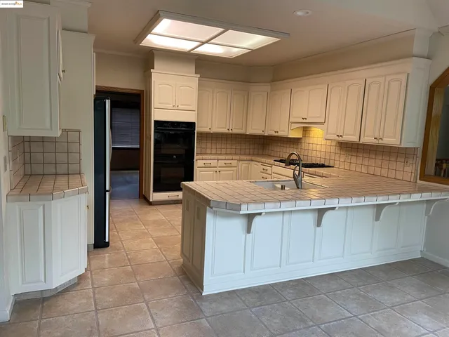 a kitchen with stainless steel appliances kitchen island granite countertop a refrigerator and a sink
