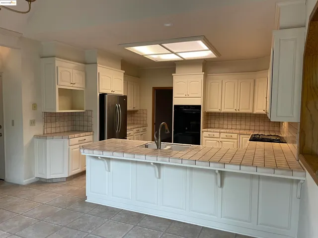 a kitchen with granite countertop a sink stainless steel appliances and cabinets