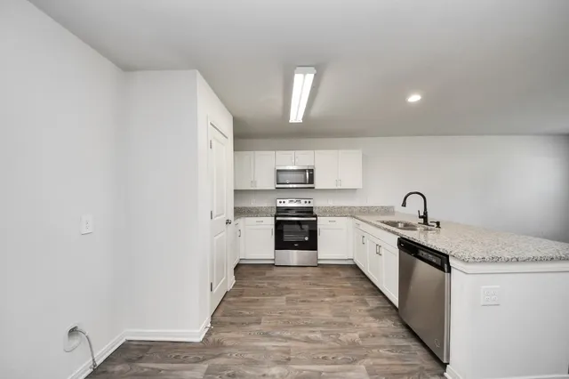 a large kitchen with granite countertop a sink and white stainless steel appliances
