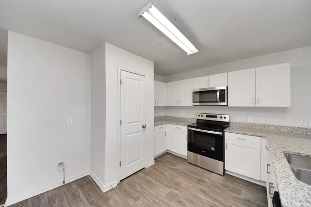 a kitchen with stainless steel appliances a sink cabinets and wooden floor