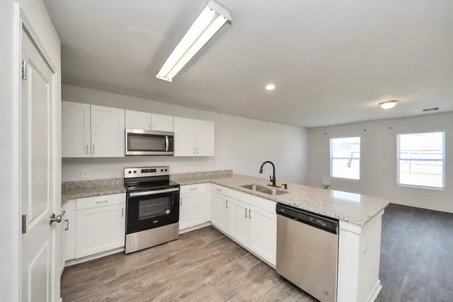 a kitchen with stainless steel appliances granite countertop a sink a stove a refrigerator cabinets and a window