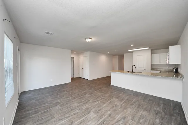 a view of a kitchen with kitchen island a sink wooden floor and a refrigerator