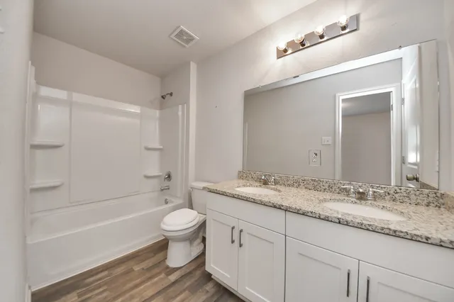a white bath tub sitting next to a white toilet and vanity