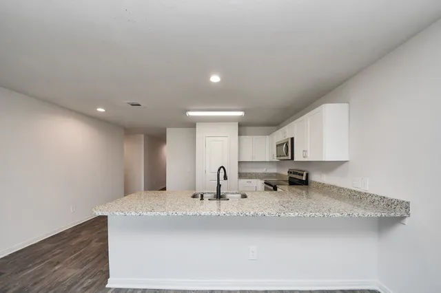 a kitchen with stainless steel appliances granite countertop a sink a stove and a refrigerator with wooden floor