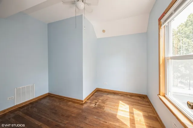 an empty room with wooden floor ceiling fan and windows
