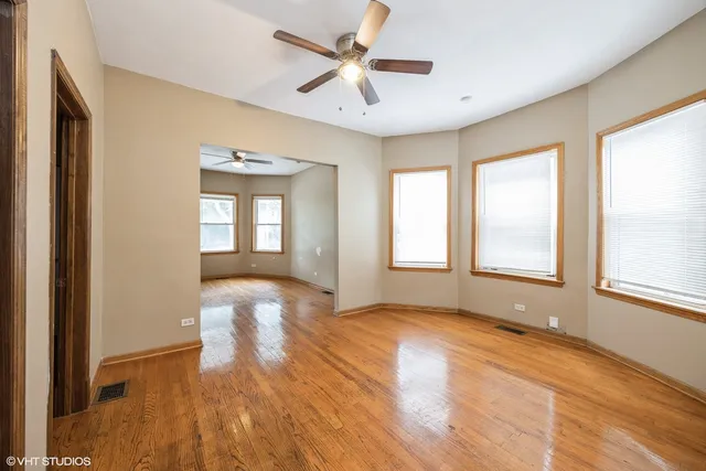 a view of empty room with wooden floor and fan