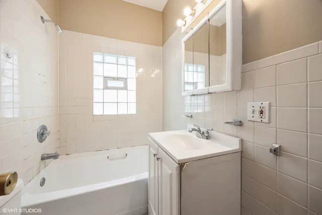 a bathroom with a bathtub a sink a window and mirror