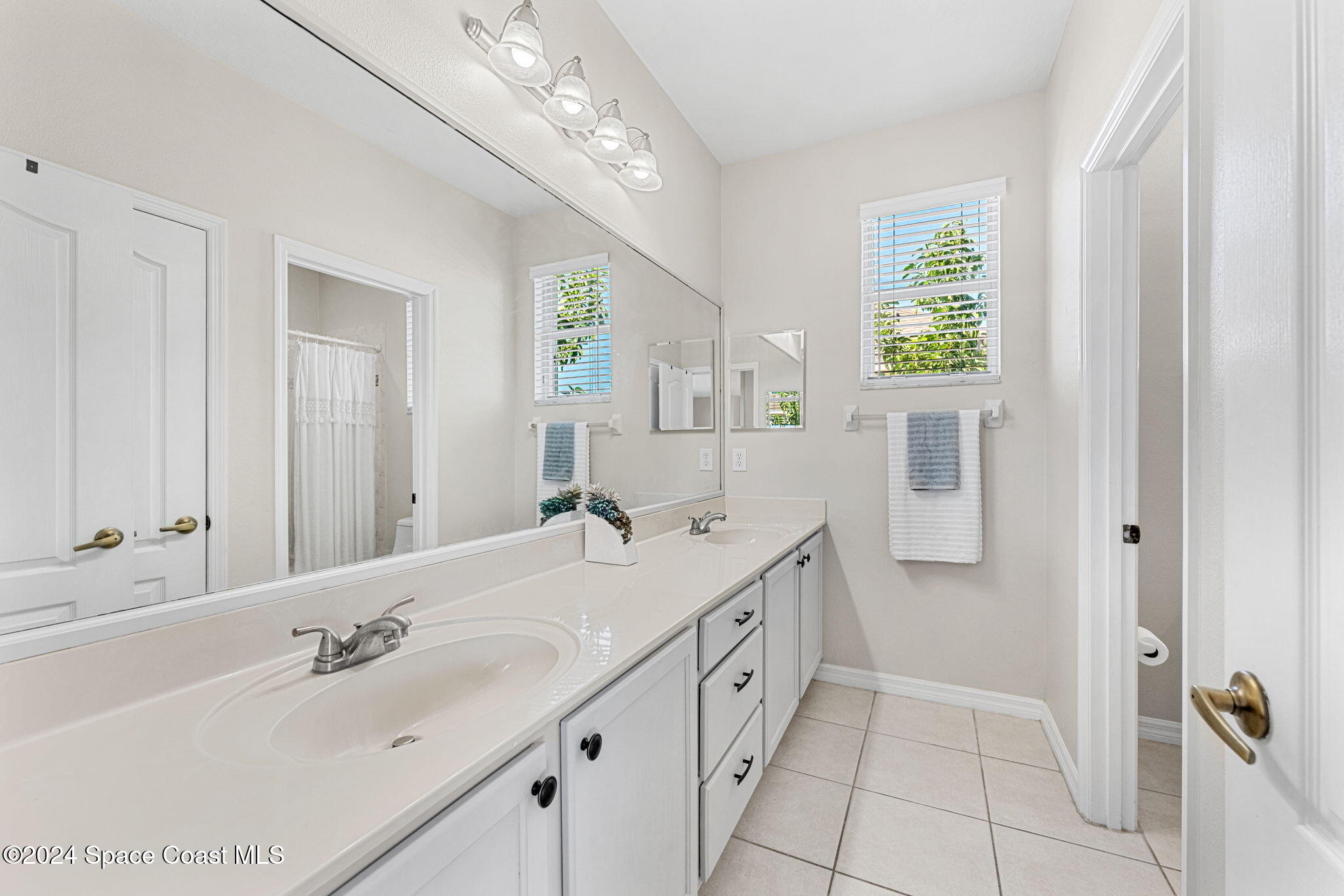 3416 Peninsula Circle Melbourne, FL 32940 - Photo 30 of 61 a bathroom with a double vanity sink and a mirror