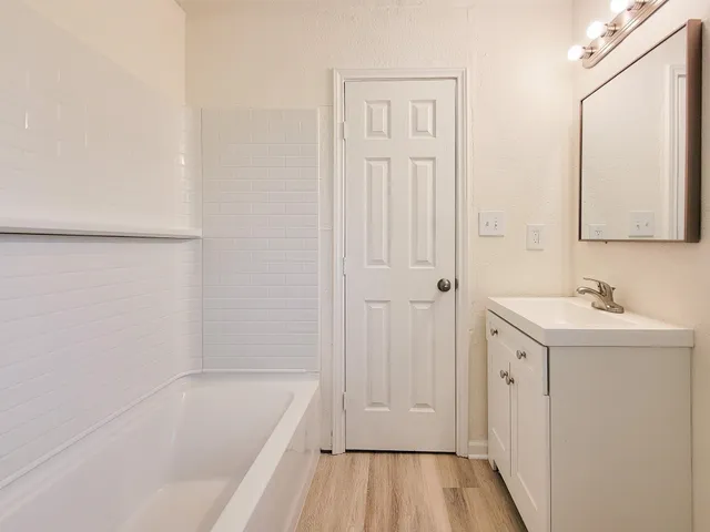 a bathroom with a tub sink and mirror